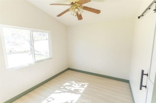 unfurnished room featuring light wood-style floors, baseboards, a ceiling fan, and lofted ceiling