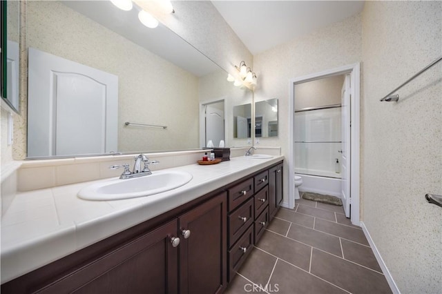 full bathroom with a sink, toilet, double vanity, and tile patterned flooring