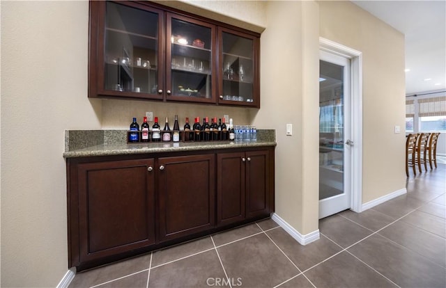 bar with dark tile patterned flooring, a dry bar, and baseboards
