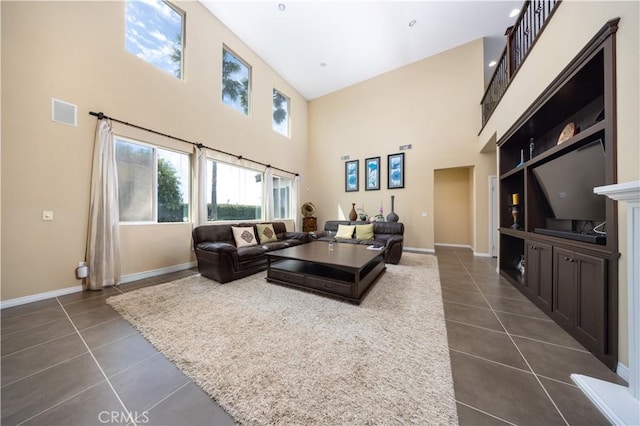living room featuring a towering ceiling, baseboards, and dark tile patterned flooring
