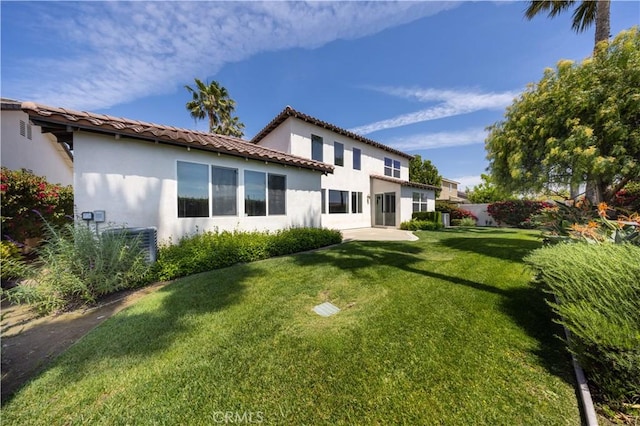 rear view of house featuring central AC, a lawn, a tile roof, fence, and stucco siding