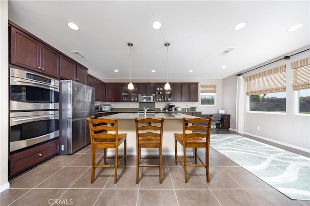 kitchen with visible vents, appliances with stainless steel finishes, light tile patterned flooring, and a kitchen bar