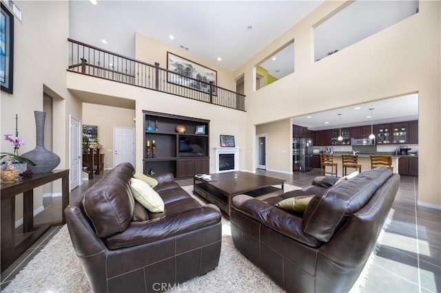 living area featuring a towering ceiling, baseboards, and recessed lighting
