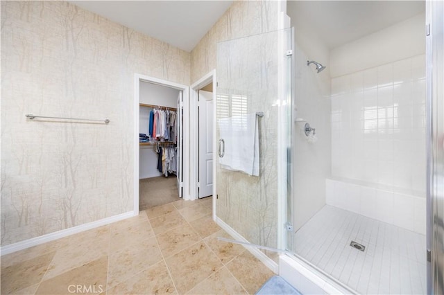 bathroom featuring a stall shower, a walk in closet, and tile patterned floors