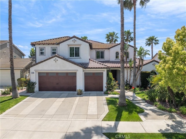 mediterranean / spanish-style home with a garage, driveway, a tiled roof, and stucco siding