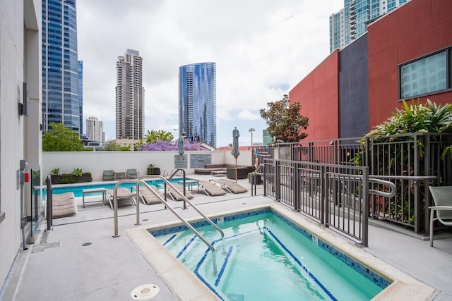 pool with a community hot tub, a patio, and a city view