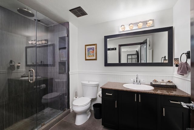 bathroom with vanity, tile patterned floors, a wainscoted wall, toilet, and visible vents