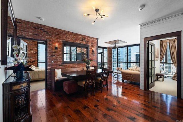 dining space with brick wall, an inviting chandelier, and hardwood / wood-style flooring