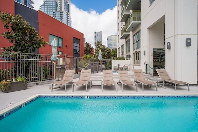 community pool featuring a view of city, a patio area, and fence