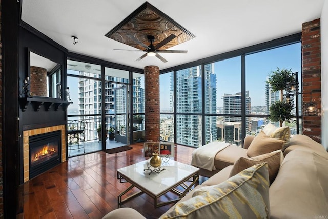living area with a glass covered fireplace, a city view, hardwood / wood-style floors, and a ceiling fan