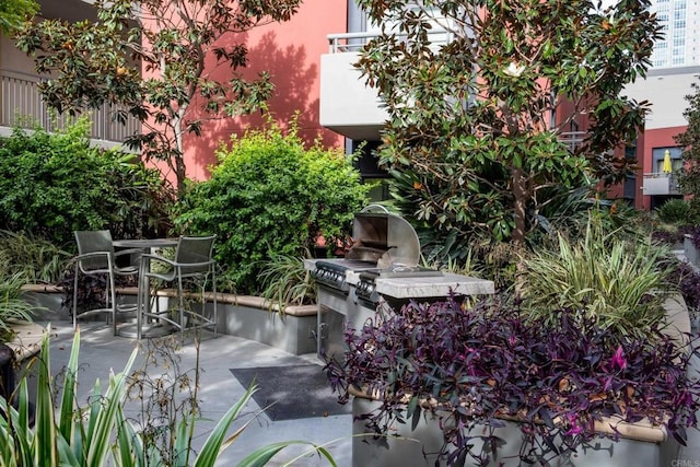 view of patio / terrace with grilling area, a balcony, outdoor dining area, and exterior kitchen