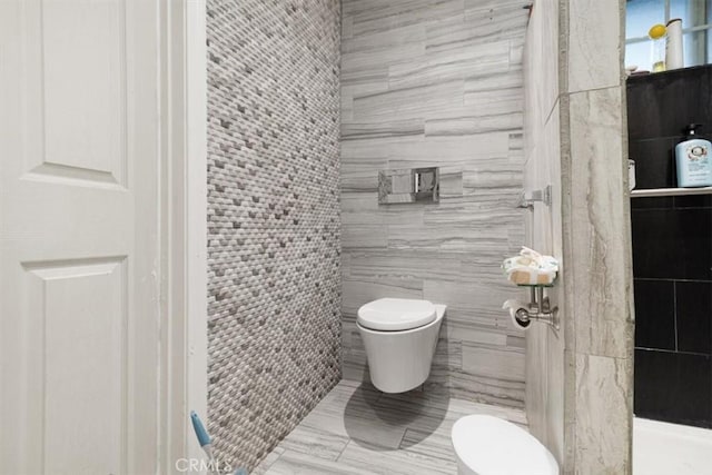 bathroom featuring tile walls and toilet