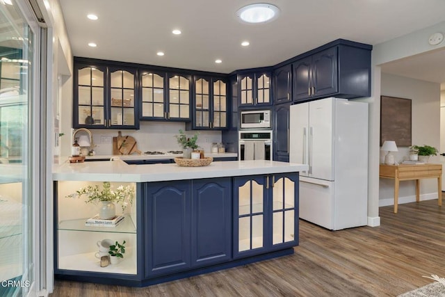 kitchen with stainless steel oven, freestanding refrigerator, built in microwave, dark wood finished floors, and a sink