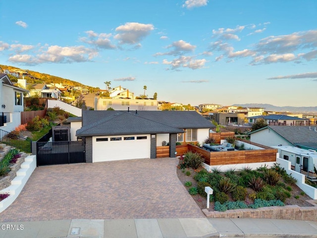 ranch-style home with an attached garage, fence, a residential view, and decorative driveway