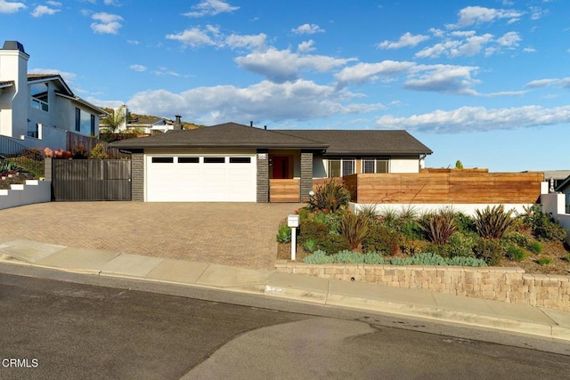 single story home with an attached garage, fence, and decorative driveway