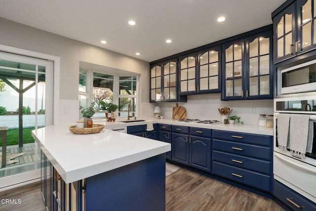 kitchen featuring white appliances, dark wood-style flooring, light countertops, and blue cabinets