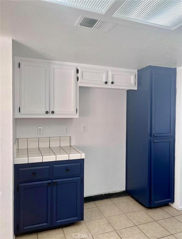 8109 Birch St, Bakersfield, CA 93311 - kitchen with blue cabinetry, white cabinetry, tile counters, and light tile patterned floors