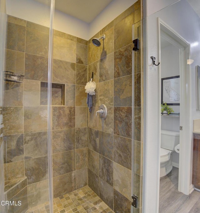full bathroom featuring wood finished floors, toilet, and a stall shower
