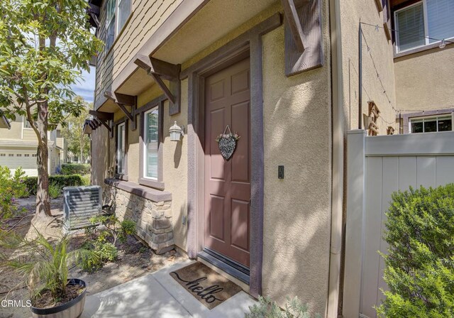 doorway to property featuring central AC, stone siding, and stucco siding