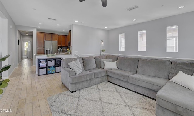 living area with a ceiling fan, light wood-type flooring, baseboards, visible vents, and recessed lighting
