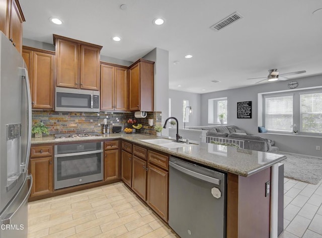 kitchen with a sink, open floor plan, a peninsula, appliances with stainless steel finishes, and visible vents