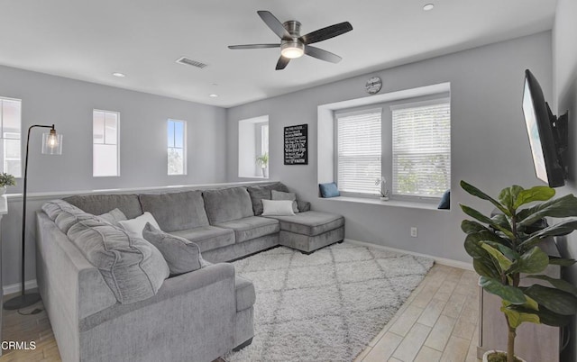 living room with a ceiling fan, wood finished floors, visible vents, and plenty of natural light