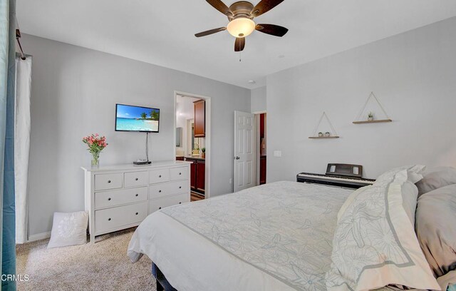 bedroom featuring a ceiling fan, ensuite bathroom, and light colored carpet