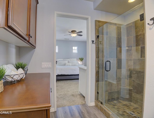 ensuite bathroom featuring a shower stall, a ceiling fan, wood finished floors, ensuite bathroom, and baseboards