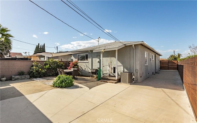 view of front of house featuring a patio, central AC unit, stucco siding, and a fenced backyard