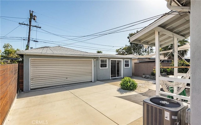 exterior space featuring central AC unit, stucco siding, fence, and a detached garage
