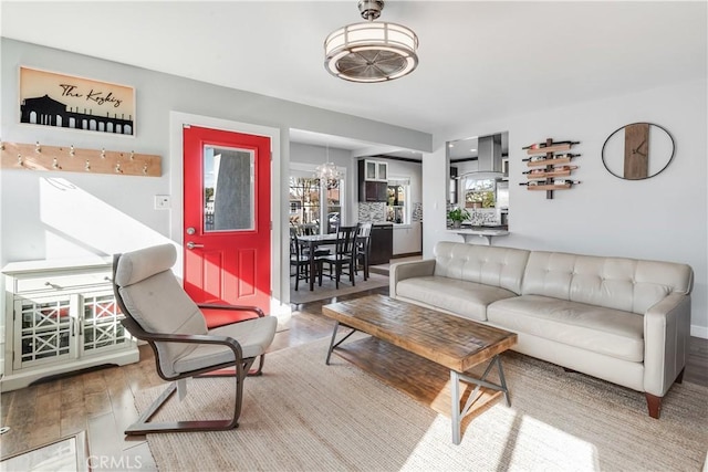 living area with wood finished floors, an inviting chandelier, and baseboards