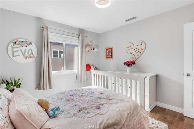 bedroom featuring visible vents, baseboards, and wood finished floors