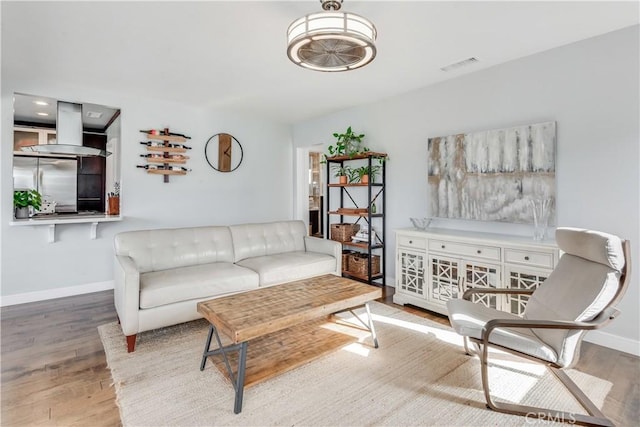 living area featuring visible vents, baseboards, and wood finished floors