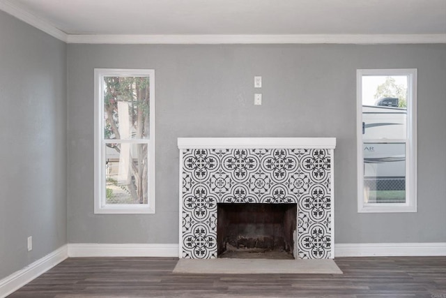 unfurnished living room with wood finished floors, a fireplace, ornamental molding, and baseboards