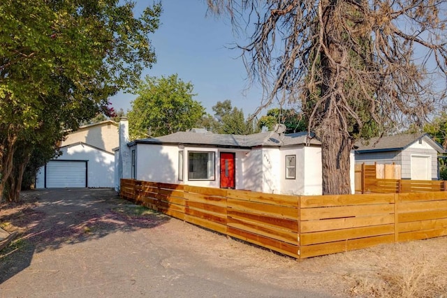 view of front of property with a fenced front yard, a garage, an outdoor structure, stucco siding, and driveway