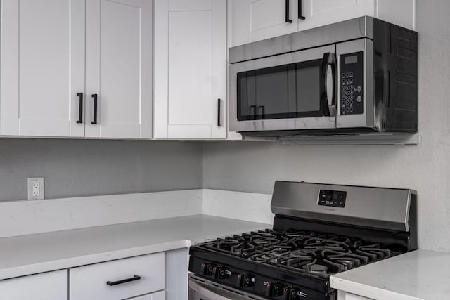 kitchen with white cabinetry, appliances with stainless steel finishes, and light stone countertops