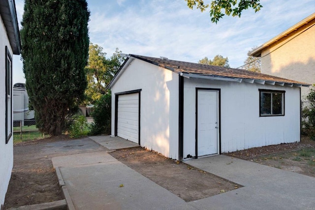 view of outdoor structure with an outbuilding, fence, and concrete driveway