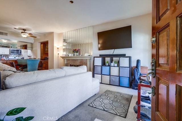 living area with light carpet, a ceiling fan, and visible vents