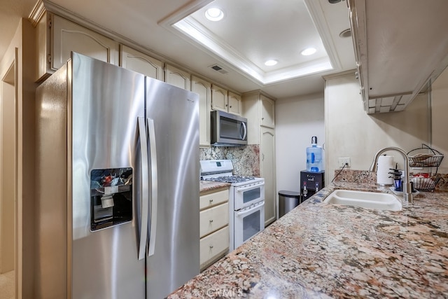kitchen featuring recessed lighting, stainless steel appliances, a tray ceiling, visible vents, and a sink