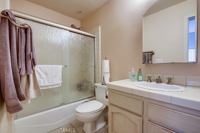 bathroom with tile patterned floors, vanity, enclosed tub / shower combo, and toilet