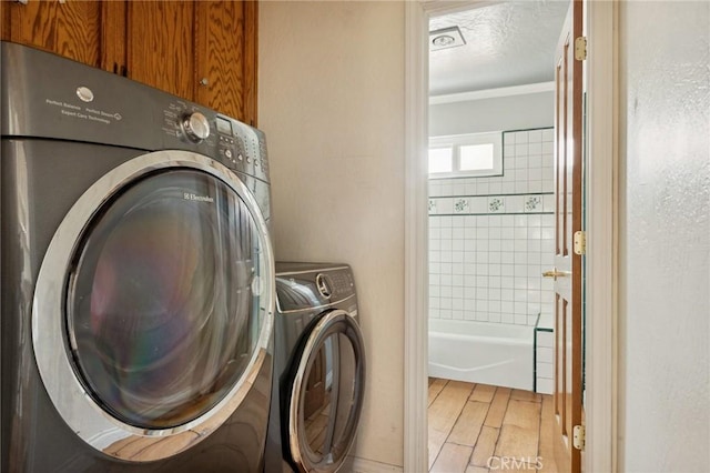 24540 Horst Dr, Crestline, CA 92325 - laundry area with cabinet space, ornamental molding, light wood-style flooring, a textured ceiling, and independent washer and dryer