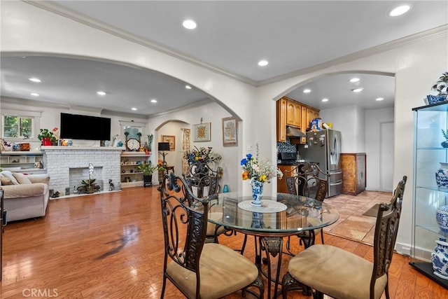 1435 W 50th St, Los Angeles, CA 90062 - dining room with crown molding, arched walkways, light wood-style floors, recessed lighting, and a fireplace