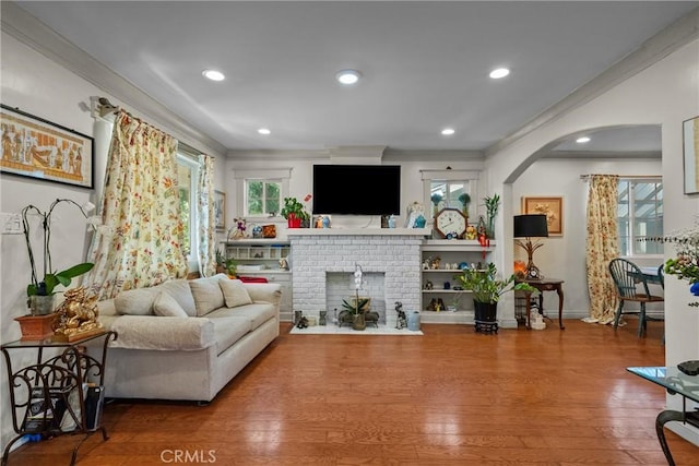 1435 W 50th St, Los Angeles, CA 90062 - living room featuring wood finished floors, a brick fireplace, arched walkways, ornamental molding, and recessed lighting