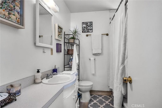 bathroom featuring toilet, tile patterned floors, vanity, and curtained shower