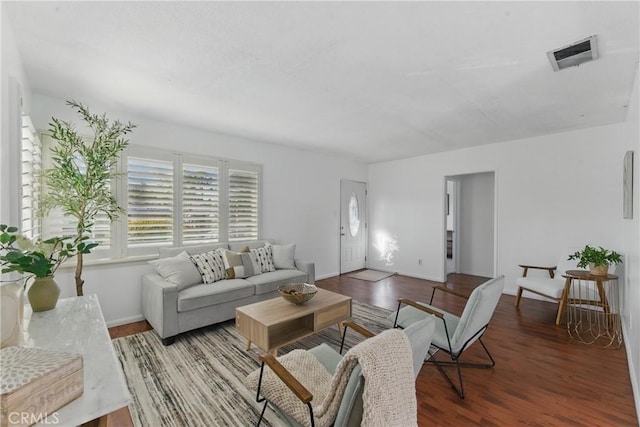 living area with wood finished floors, visible vents, and baseboards