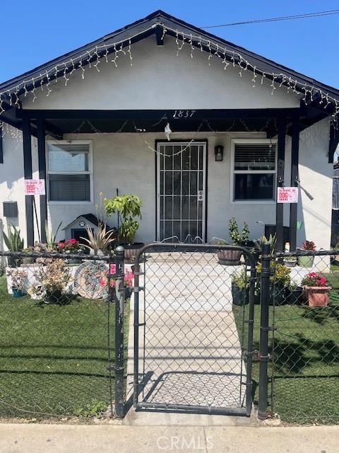 view of front facade featuring fence, stucco siding, and a gate