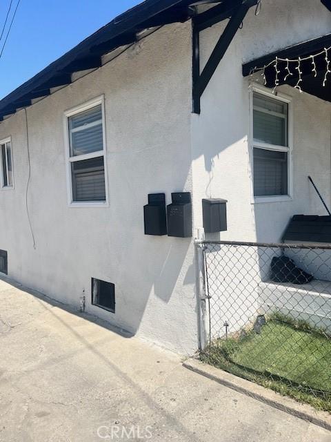 view of side of property featuring stucco siding and fence