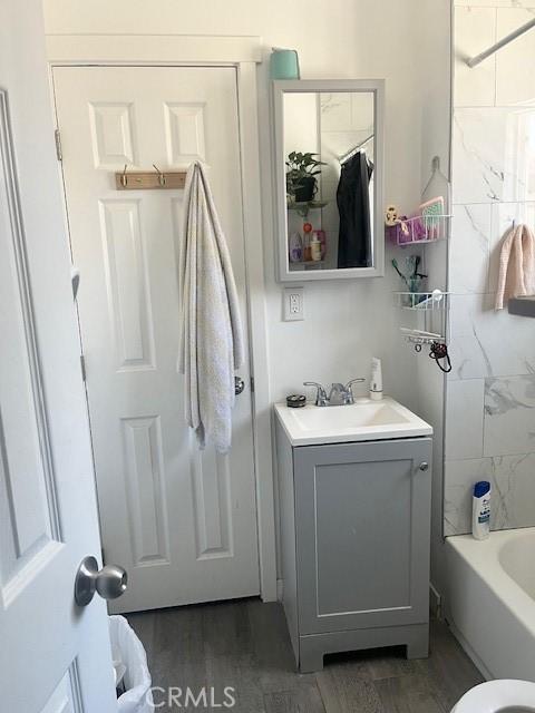 full bathroom with bathing tub / shower combination, vanity, and wood finished floors