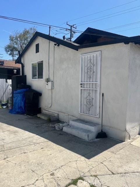 view of side of home featuring entry steps, fence, and stucco siding