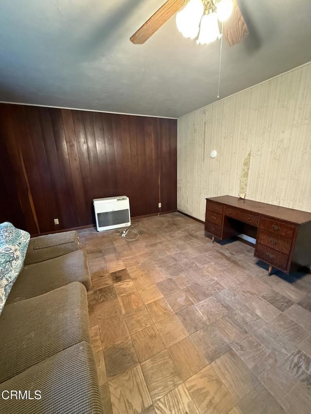 unfurnished living room with wood walls, heating unit, and ceiling fan